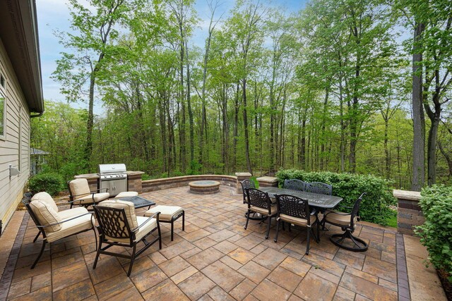 view of patio with grilling area, outdoor dining space, and an outdoor living space with a fire pit