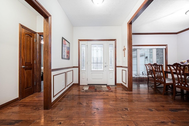 foyer entrance with plenty of natural light, a decorative wall, a wainscoted wall, wood finished floors, and a textured ceiling