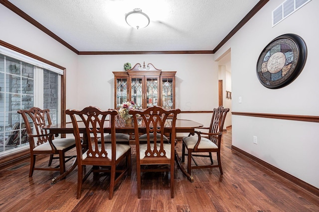 dining area with a textured ceiling, wood finished floors, crown molding, and baseboards