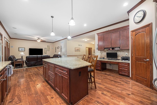 kitchen with crown molding, dark wood-style flooring, decorative backsplash, pendant lighting, and a kitchen breakfast bar