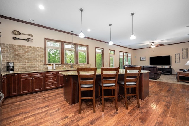 bar area with dark wood-style floors, ornamental molding, pendant lighting, a sink, and black electric cooktop