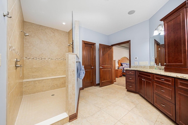 ensuite bathroom featuring a walk in shower, vanity, and tile patterned floors