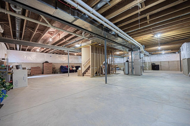 unfinished below grade area featuring heating unit, water heater, and stairs