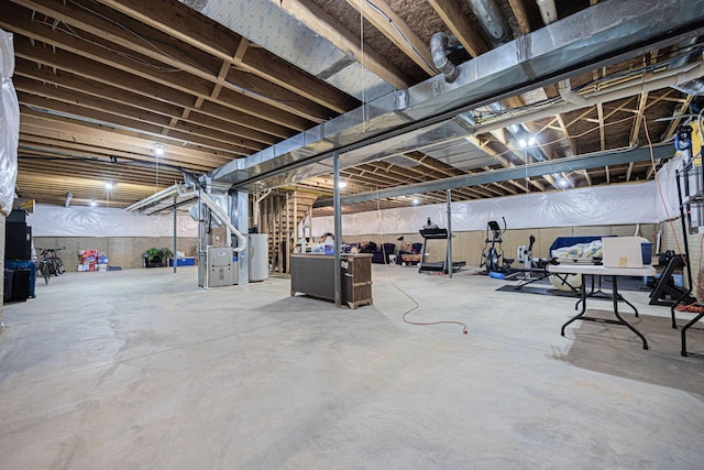 unfinished basement with stairway, heating unit, and water heater