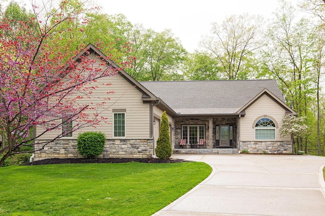 view of front of house featuring stone siding, a front yard, and concrete driveway