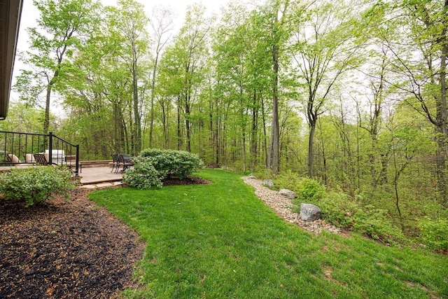 view of green lawn featuring a wooden deck