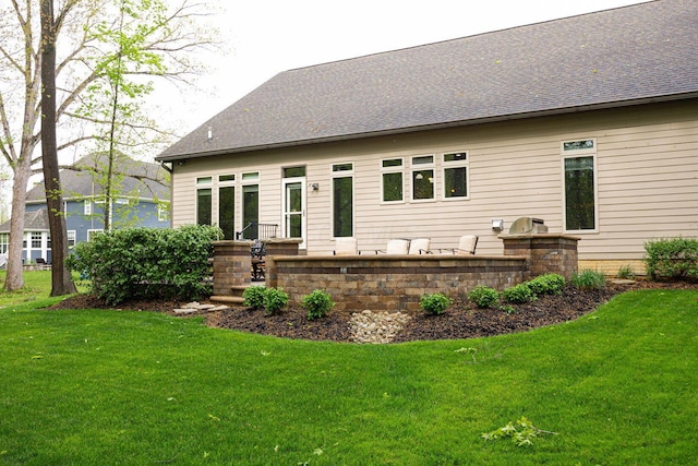 rear view of property with a yard and a shingled roof