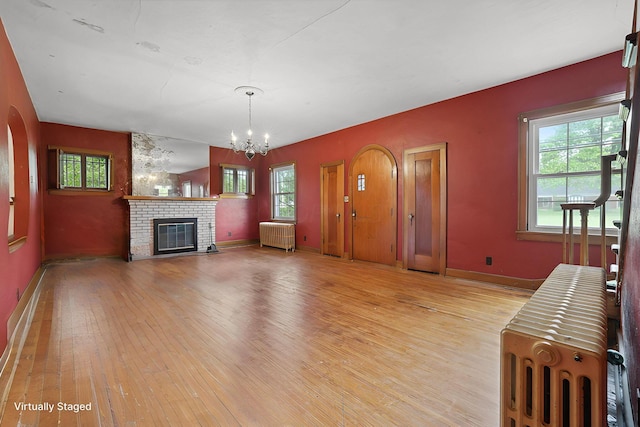 5 Baltimore Somerset Rd NE, Baltimore, OH 43105 - unfurnished living room featuring radiator, light wood finished floors, a chandelier, and a brick fireplace