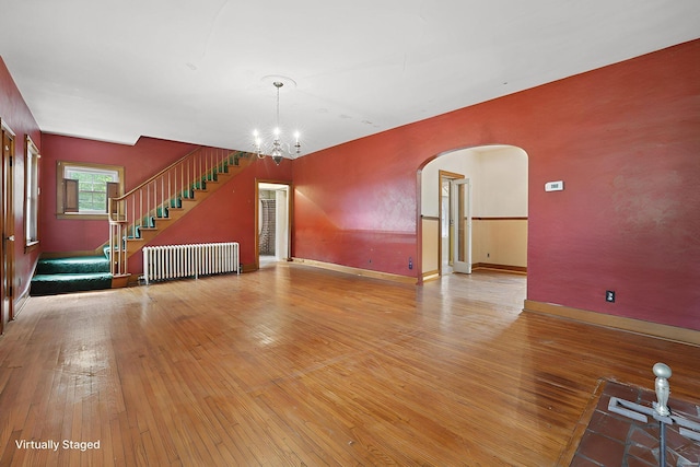 5 Baltimore Somerset Rd NE, Baltimore, OH 43105 - unfurnished living room with radiator heating unit, arched walkways, wood-type flooring, and a chandelier