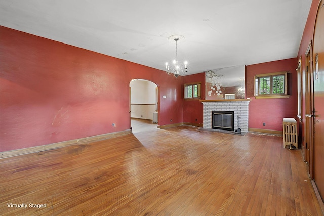 5 Baltimore Somerset Rd NE, Baltimore, OH 43105 - unfurnished living room with arched walkways, light wood-style floors, radiator heating unit, a brick fireplace, and a chandelier