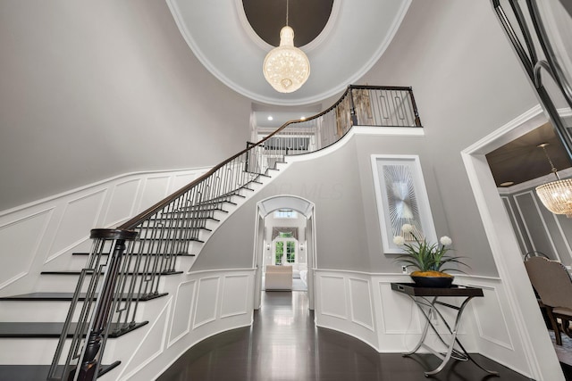 7347 Lambton Park Rd, New Albany, OH 43054 - stairs featuring a decorative wall, a chandelier, wainscoting, a high ceiling, and arched walkways