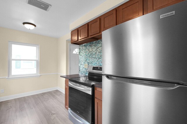 1666 Northridge Rd, Columbus, OH 43224 - kitchen with stainless steel appliances, brown cabinets, light wood finished floors, decorative backsplash, and dark countertops