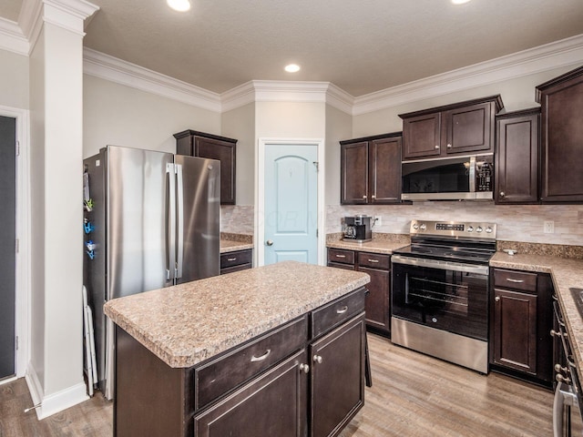 9035 Strawser St, Orient, OH 43146 - kitchen featuring appliances with stainless steel finishes, light wood-style floors, dark brown cabinetry, light countertops, and crown molding