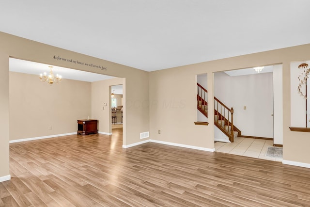 5556 Falco Dr, Westerville, OH 43081 - unfurnished living room featuring light wood-type flooring, a chandelier, stairs, and baseboards