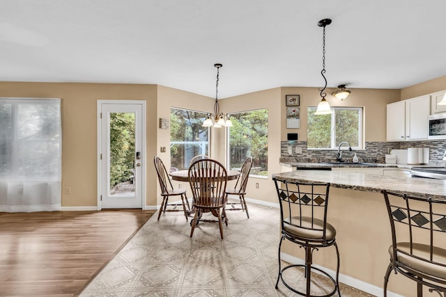 5556 Falco Dr, Westerville, OH 43081 - kitchen featuring a sink, a kitchen bar, light wood finished floors, a chandelier, and decorative light fixtures
