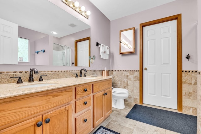 5556 Falco Dr, Westerville, OH 43081 - bathroom with tile walls, a shower with shower door, double vanity, wainscoting, and toilet