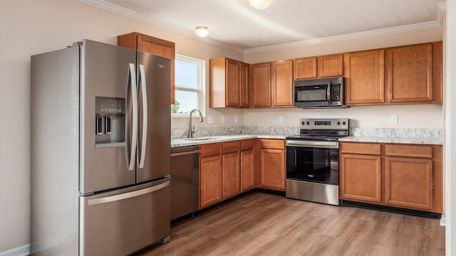 776 Brevard Cir, Pickerington, OH 43147 - kitchen featuring appliances with stainless steel finishes, a sink, light countertops, light wood-type flooring, and crown molding
