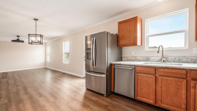 776 Brevard Cir, Pickerington, OH 43147 - kitchen featuring a sink, appliances with stainless steel finishes, brown cabinets, ornamental molding, and wood finished floors