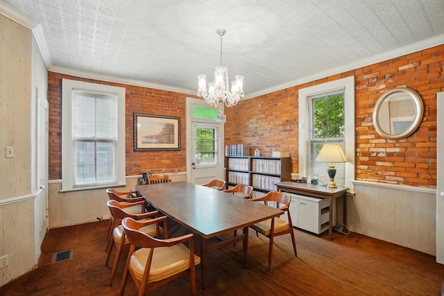 699 S Front St, Columbus, OH 43206 - dining area with a chandelier, ornamental molding, brick wall, and wooden walls