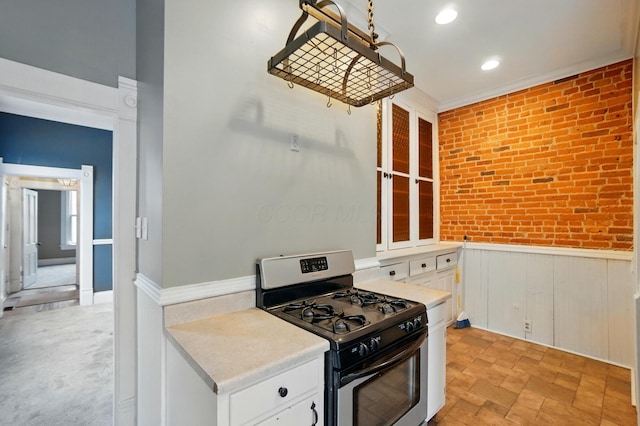 696 Bank St, Columbus, OH 43206 - kitchen with gas range, wainscoting, white cabinets, light countertops, and brick wall