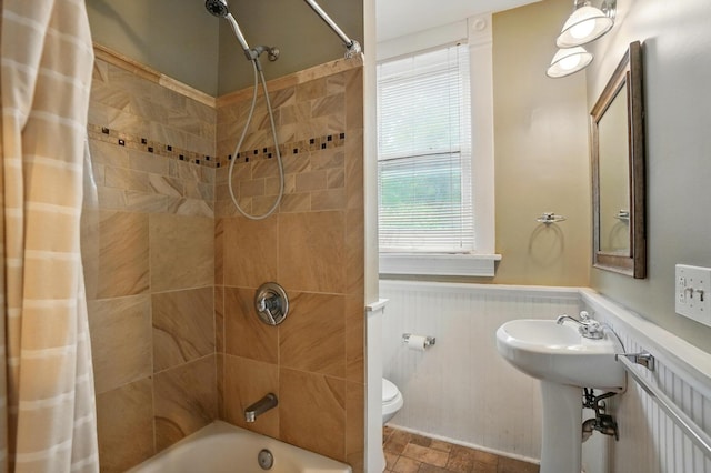 696 Bank St, Columbus, OH 43206 - full bath with a wainscoted wall, toilet, shower / bath combo with shower curtain, stone finish floors, and a sink