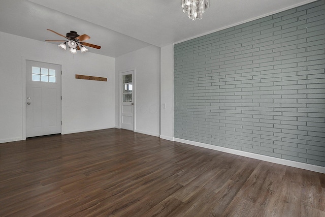 entryway with ceiling fan, dark wood finished floors, a chandelier, brick wall, and baseboards
