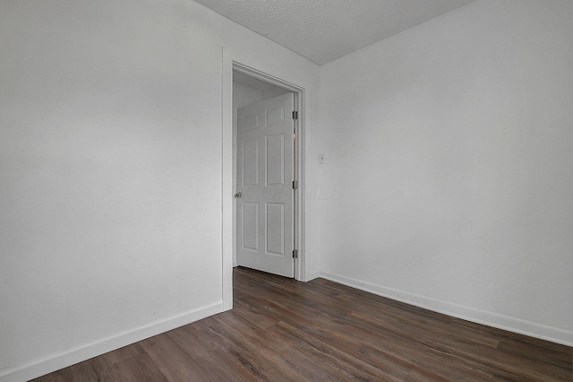 empty room with dark wood-type flooring, baseboards, and a textured ceiling