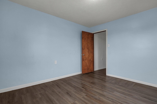 unfurnished room with dark wood finished floors and baseboards