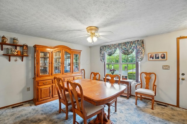 dining area with ceiling fan, light colored carpet, baseboards, and a textured ceiling