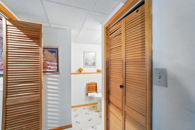 hall with a paneled ceiling and baseboards