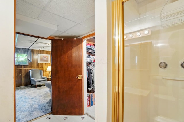 hallway with a drop ceiling and wood walls