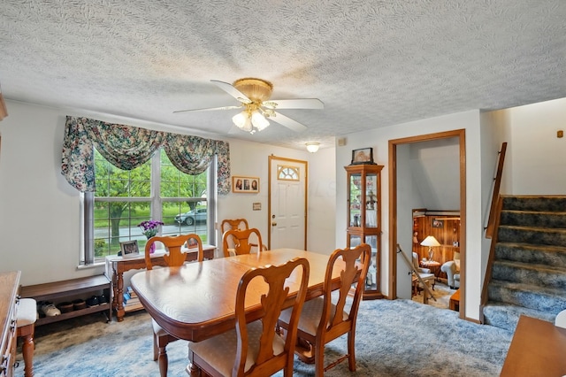 carpeted dining area with a ceiling fan, stairway, and a textured ceiling