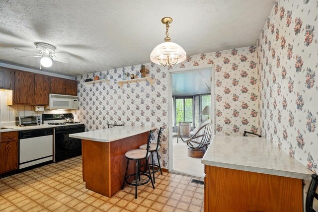 kitchen with white appliances, wallpapered walls, a peninsula, light countertops, and a breakfast bar area