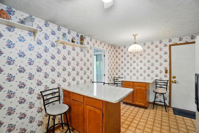 kitchen featuring wallpapered walls, a peninsula, light countertops, open shelves, and brown cabinetry