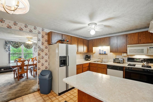 kitchen featuring white appliances, a ceiling fan, a sink, light countertops, and brown cabinetry