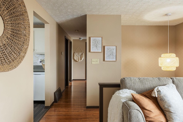 hallway featuring wood finished floors, a textured ceiling, and baseboards