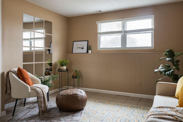 sitting room with tile patterned floors, a wainscoted wall, and baseboards