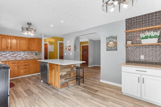 113 Bridgeport Way, Delaware, OH 43015 - kitchen with dishwasher, arched walkways, decorative backsplash, a kitchen island, and light countertops