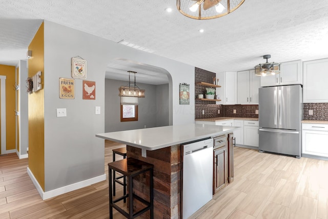 113 Bridgeport Way, Delaware, OH 43015 - kitchen featuring freestanding refrigerator, dishwashing machine, arched walkways, open shelves, and a textured ceiling