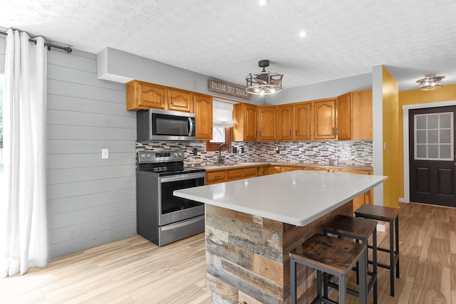 113 Bridgeport Way, Delaware, OH 43015 - kitchen featuring appliances with stainless steel finishes, tasteful backsplash, light wood-style flooring, brown cabinets, and light countertops