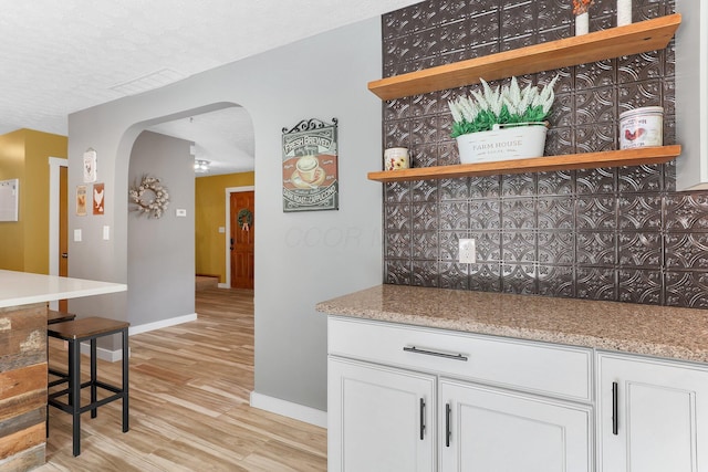 113 Bridgeport Way, Delaware, OH 43015 - kitchen with arched walkways, light wood-style floors, white cabinets, open shelves, and light stone countertops