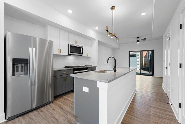 1106 Oak St Unit 12, Columbus, OH 43205 - kitchen featuring appliances with stainless steel finishes, a sink, wood finished floors, tasteful backsplash, and white cabinetry