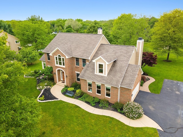 5098 Cascade Dr, Powell, OH 43065 - view of front of house with a chimney, brick siding, a shingled roof, and a front lawn