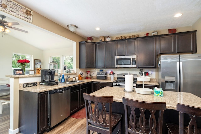 447 Wingate Pl, Mount Sterling, OH 43143 - kitchen featuring stainless steel appliances, a sink, light wood-style floors, dark brown cabinets, and a kitchen breakfast bar