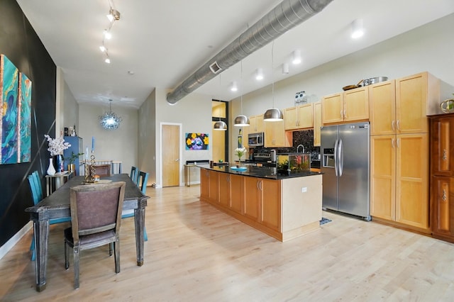 300 W Spring St Unit 515, Columbus, OH 43215 - kitchen with stainless steel appliances, light wood-style flooring, tasteful backsplash, an island with sink, and dark countertops