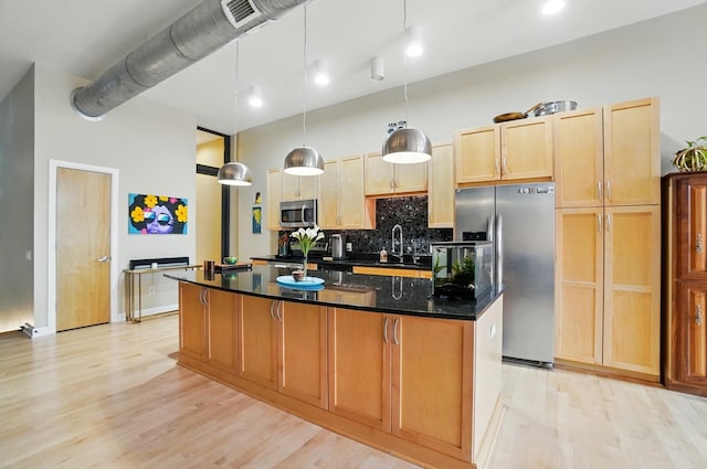 300 W Spring St Unit 515, Columbus, OH 43215 - kitchen featuring appliances with stainless steel finishes, light wood-type flooring, a kitchen island, a sink, and backsplash