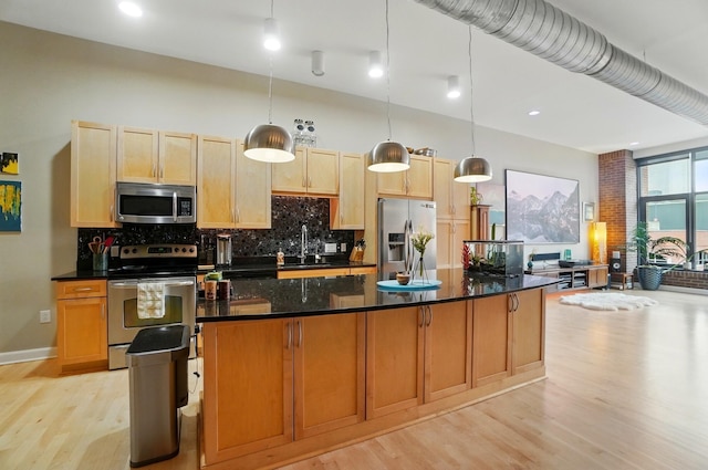 300 W Spring St Unit 515, Columbus, OH 43215 - kitchen featuring appliances with stainless steel finishes, light wood-style floors, backsplash, a sink, and a kitchen island