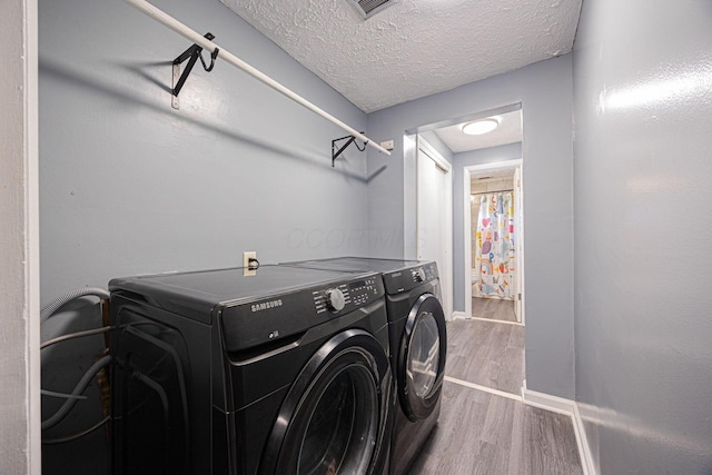 6729 Retton Rd, Reynoldsburg, OH 43068 - clothes washing area with washing machine and dryer, wood finished floors, a textured ceiling, and baseboards