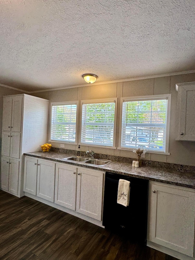 kitchen with dishwasher, a sink, a textured ceiling, dark wood-type flooring, and dark countertops