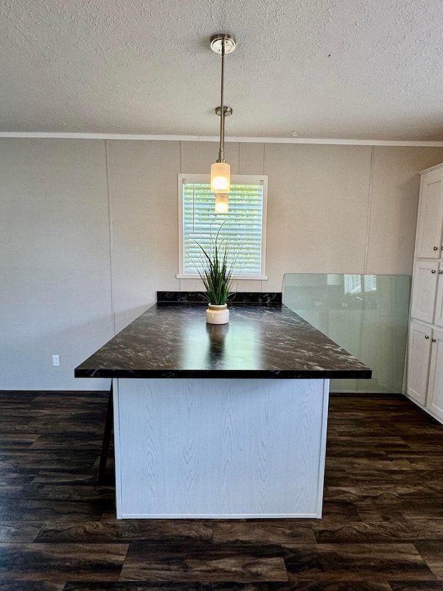 kitchen featuring dark countertops, ornamental molding, dark wood finished floors, white cabinetry, and a textured ceiling